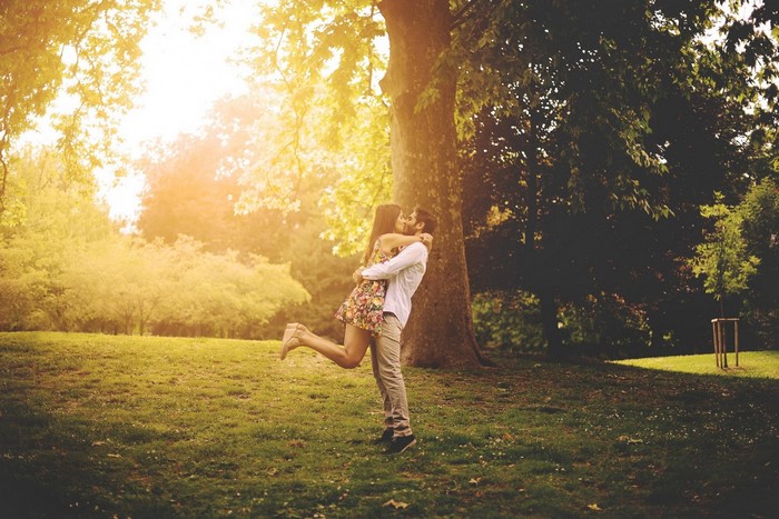 Couple kissing in a park during sunset