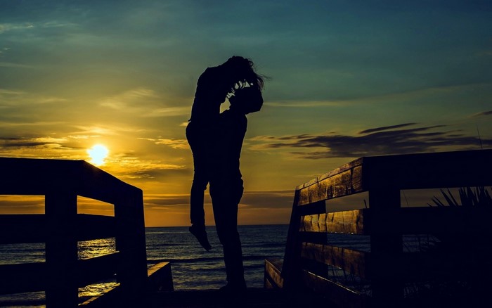 Couple silhouetted at sunset on a beach