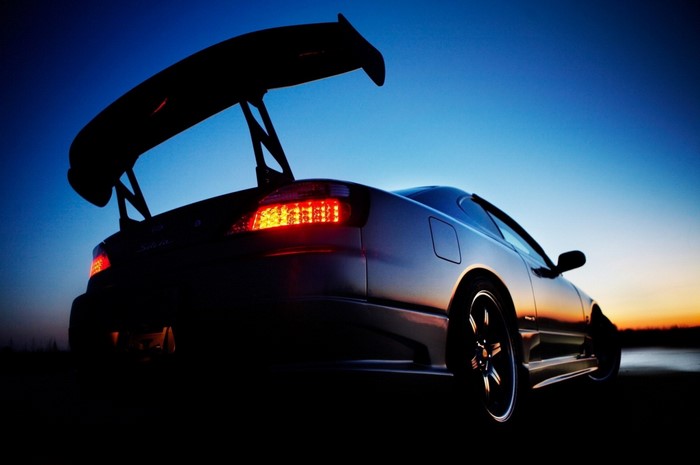 Nissan sports car with large rear spoiler at sunset