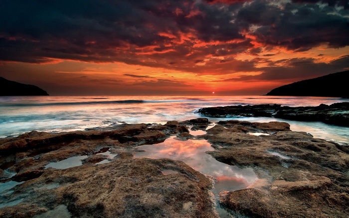 Sunset over the ocean with rocky shore