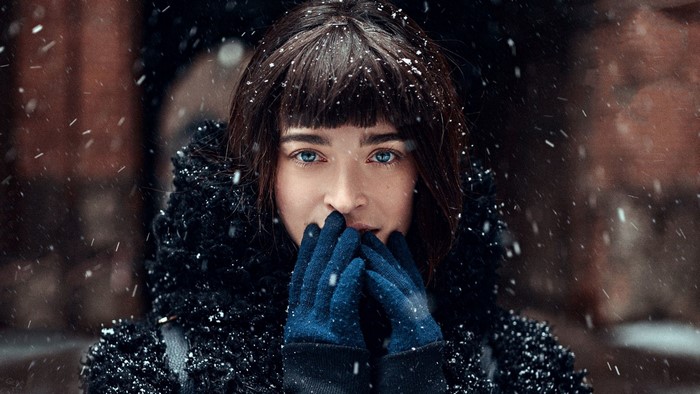 Woman in winter coat with blue eyes and gloves in snow