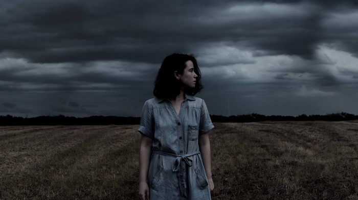 Woman in a field under a stormy sky