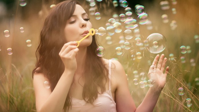 Woman blowing bubbles in a field