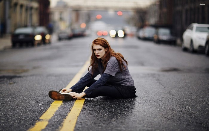 Redhead woman sitting on a wet street