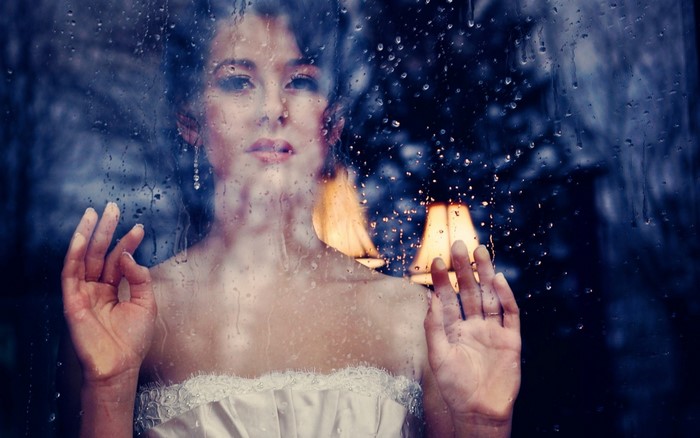 Bride looking out a rainy window