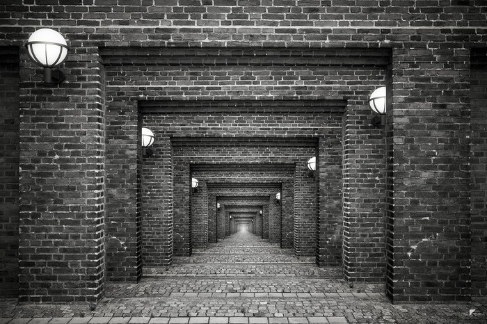 Monochrome brick alley with repeating arches and lights
