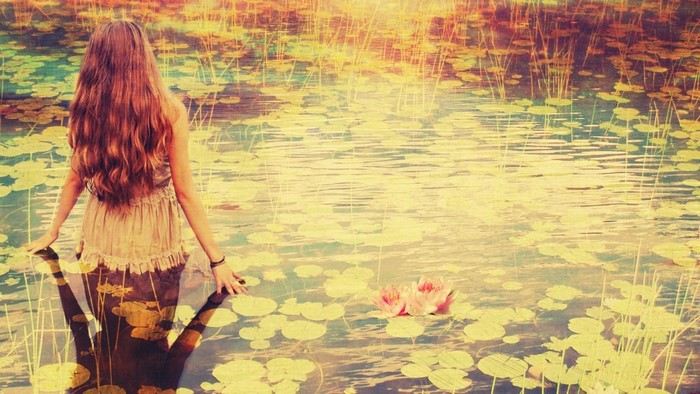 Woman with long hair by a pond with lily pads