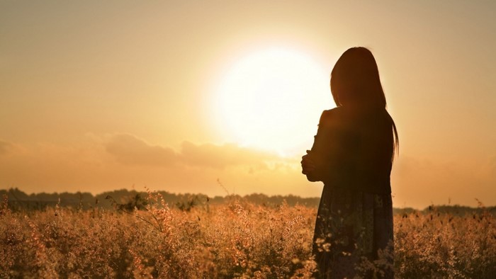 Silhouette of a woman in a field at sunset