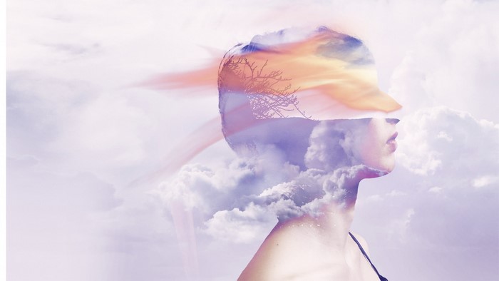 Double exposure of woman's profile with clouds and sunset