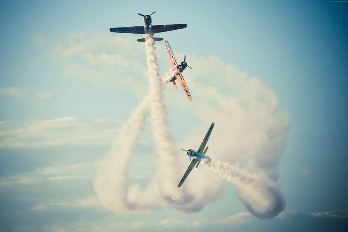 Three planes performing aerobatics with smoke trails