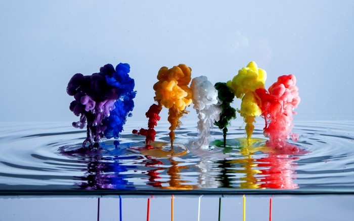 Colorful paint exploding in water with reflections