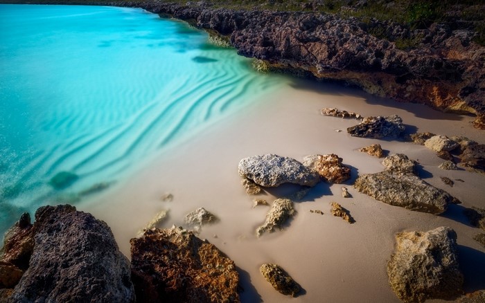 Turquoise water and rocky shore on a sandy beach