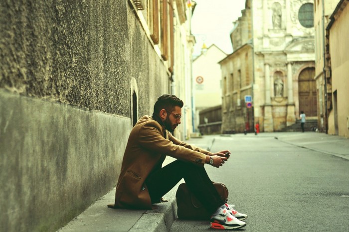 Man sitting on curb in European city street