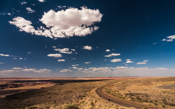 Desert landscape with a winding road under a cloudy sky