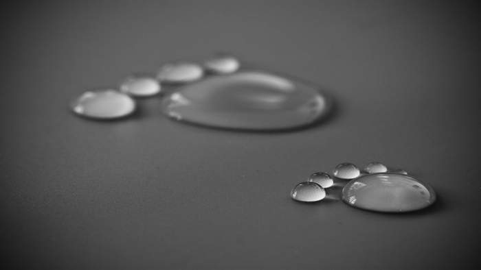Water drops forming a footprint on a dark surface
