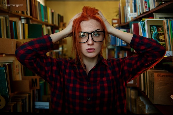 Redhead woman with glasses in a library