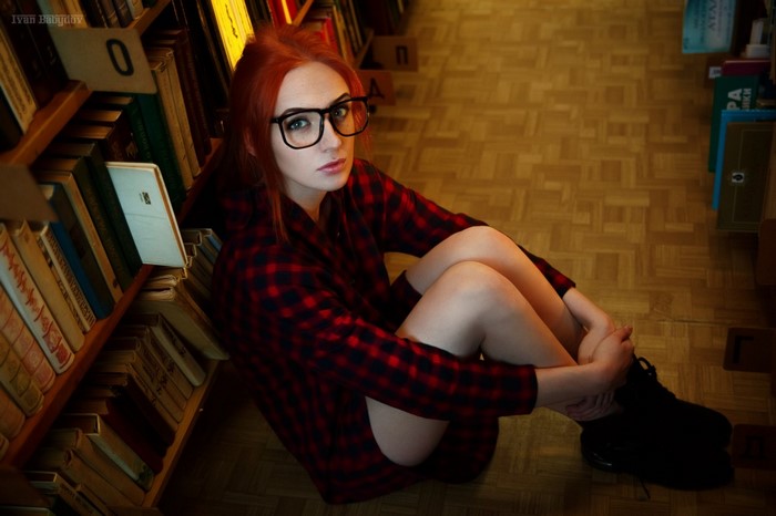 Woman with red hair and glasses in a library