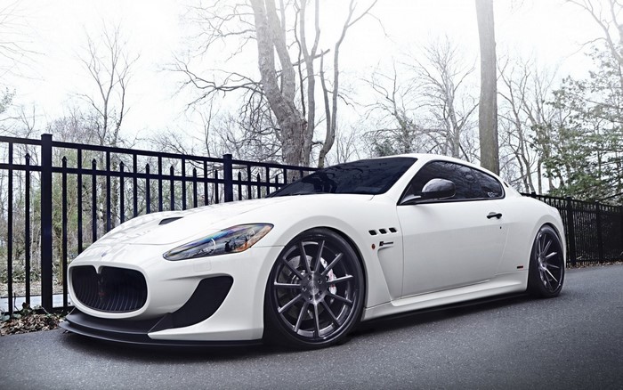 White Maserati GranTurismo parked near a black fence