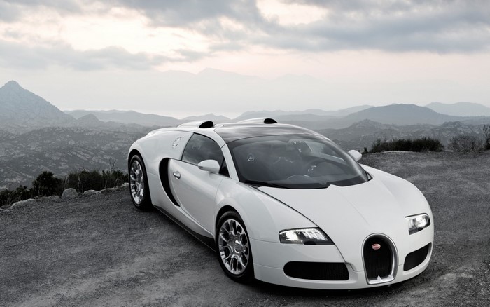 White Bugatti Veyron parked on a gravel road with mountains in the background