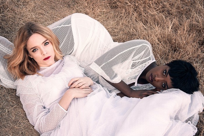 Two women in white dresses lying on dry grass