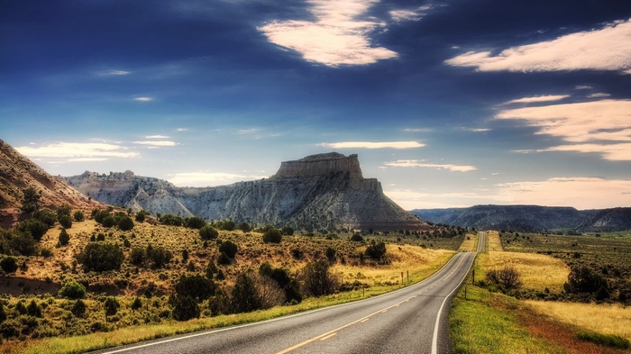 Road through desert landscape with mesas