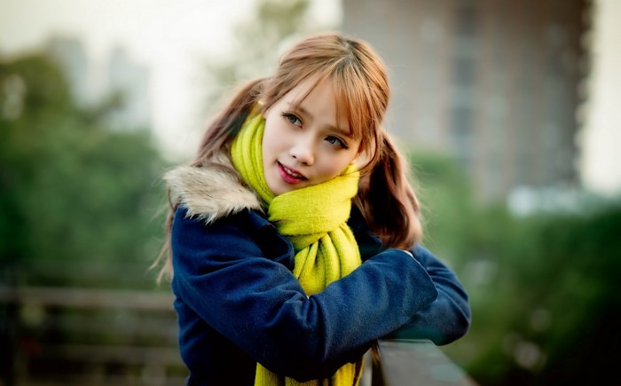Young woman with pigtails wearing a blue coat and yellow scarf
