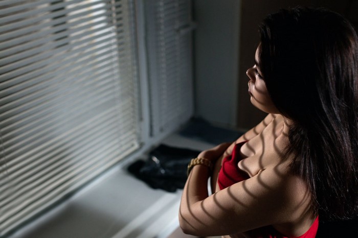 Woman in red bra by window with blinds
