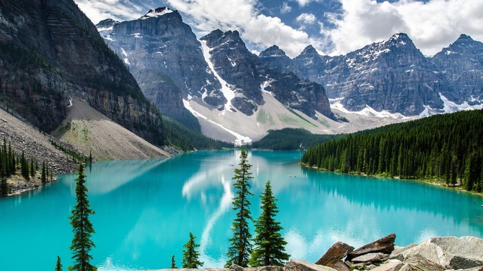 Turquoise lake surrounded by pine trees and snow-capped mountains