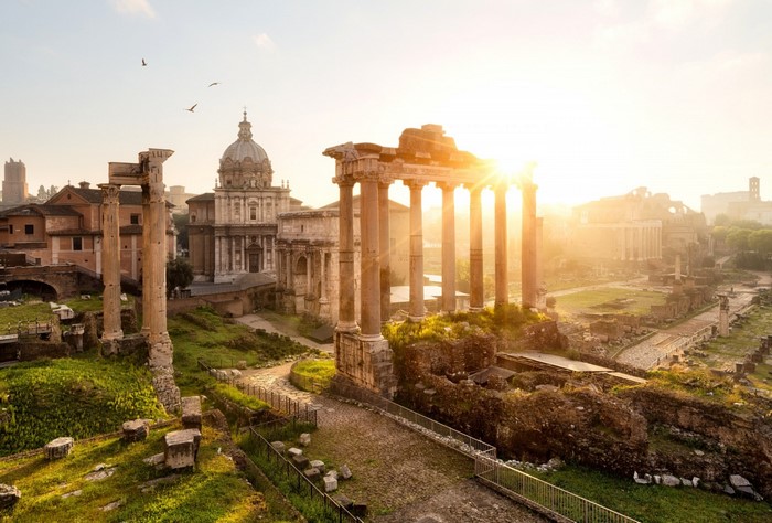 Roman Forum ruins with sunbeams and a dome building