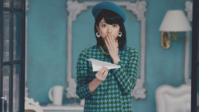 Woman in a patterned dress holding a paper airplane
