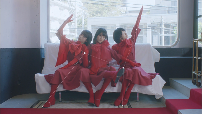 Three women in red dresses and gloves sitting