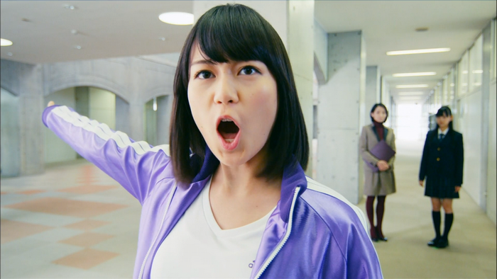 Asian woman in tracksuit pointing in a school hallway