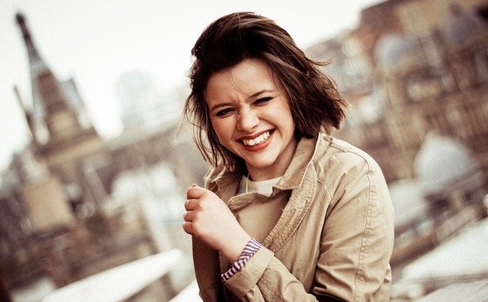 Young woman with brown hair laughing outdoors