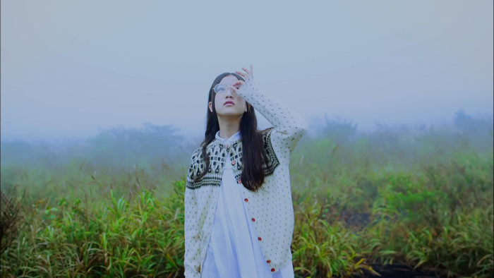 Asian woman with glasses in a cardigan outdoors