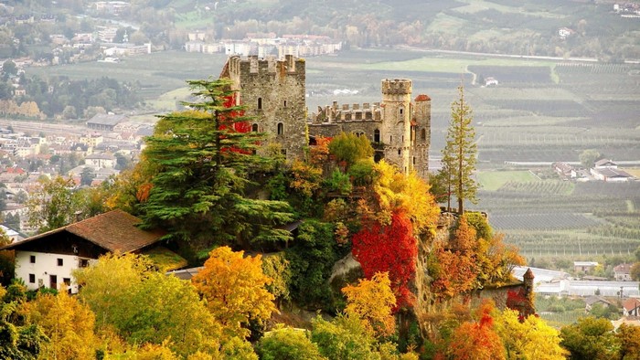 Castle on a hill with autumn foliage and a village below