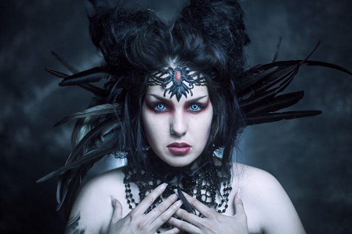 Goth woman with blue eyes and black feathers
