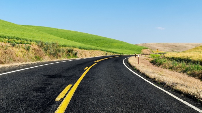 Curving asphalt road through rolling green hills