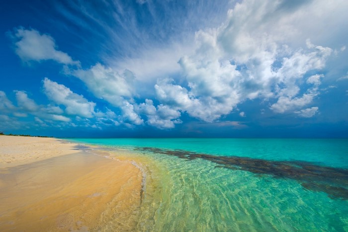 Turquoise ocean and sandy beach under a cloudy sky