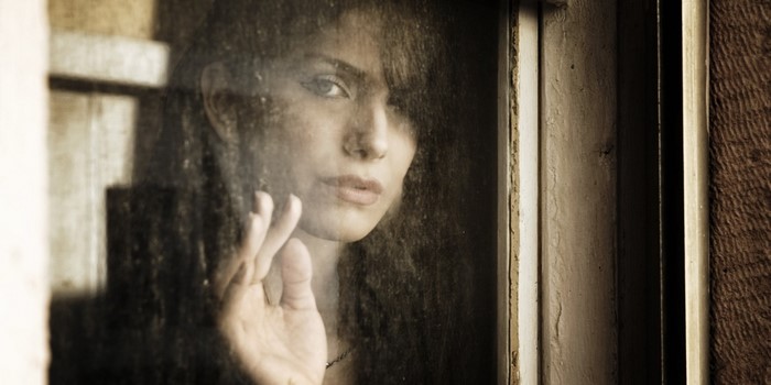 Woman looking through a dusty window