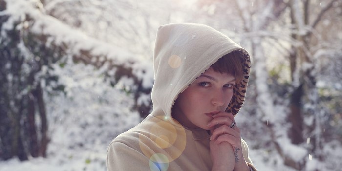Woman in hooded jacket in snowy forest