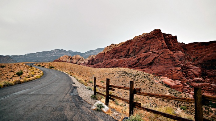 Desert road with red rock mountains and wooden fence