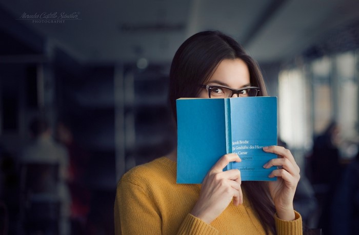 Woman wearing glasses reading a blue book