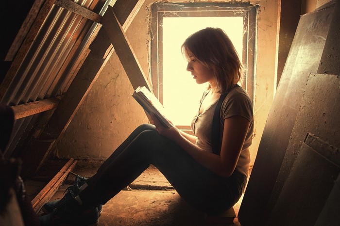 Woman reading a book in an attic