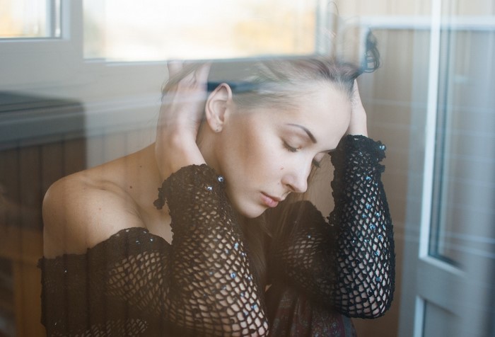 Woman with hands on head wearing black fishnet top
