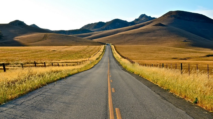 Empty road through rolling hills and fields