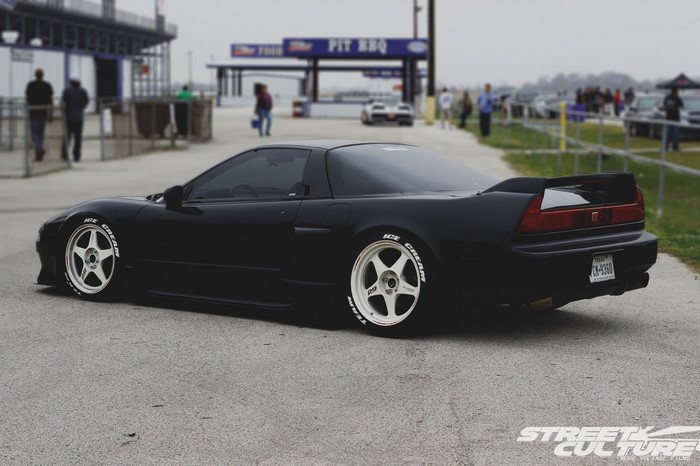 Black Honda NSX with white wheels at a race track