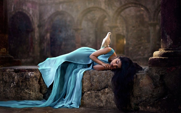 Woman in blue dress with dove in ancient temple