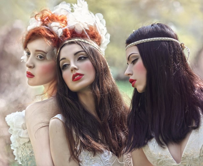 Three women with elaborate hairstyles and makeup