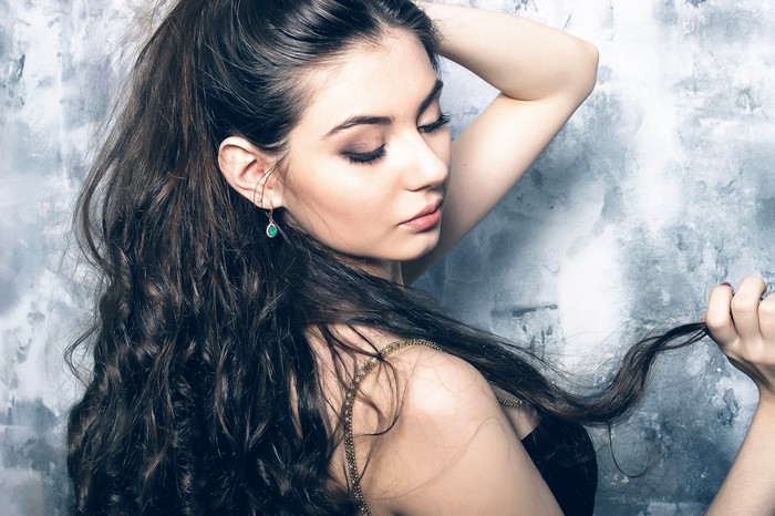 Woman with long dark curly hair and earring