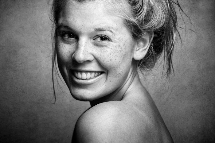 Monochrome portrait of a smiling woman with freckles